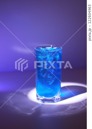 Closeup image of shining cocktail with shimmer at blue minimal background with reflections. Closeup image of shining cocktail with shimmer at blue minimal background with reflections. 122604963