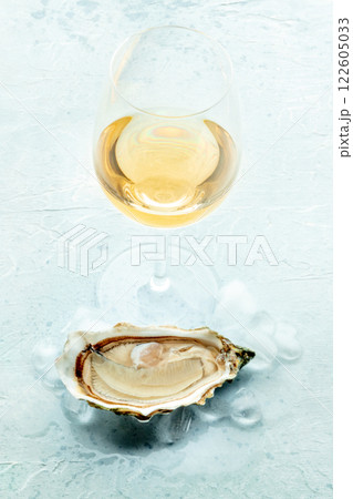Oyster with a glass of wine, on ice, on a slate background 122605033