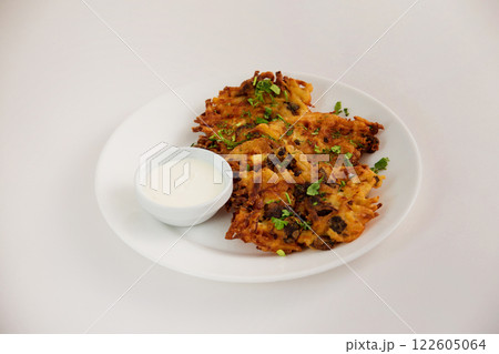 Fried brown potato pancakes with cup of cream on a plate isolated at white background. Traditional Russian meal. 122605064