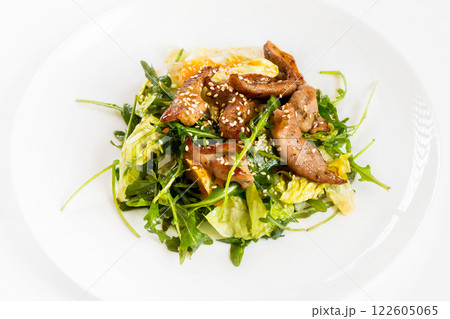 Closeup image of roasted duck at plate with green salad isolated at white background. Closeup image of roasted duck at plate with green salad isolated at white background. 122605065