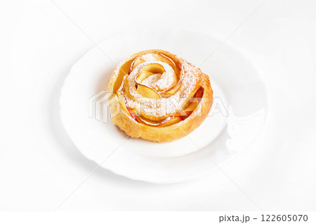Sweet rose style twisted cake of pastry puff on plate isolated at white background. Sweet rose style twisted cake of pastry puff on plate isolated at white background. 122605070