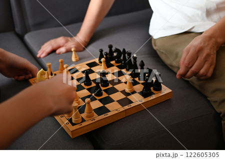 Engaging chess match between two players on a cozy couch in a living room during the afternoon 122605305