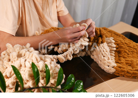 Crafting a cozy texture with yarn in warm tones during a creative session at home 122605306