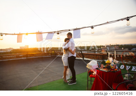 Romantic couple embraces during sunset on a rooftop celebration in the city Romantic couple embraces during sunset on a rooftop celebration in the city 122605416