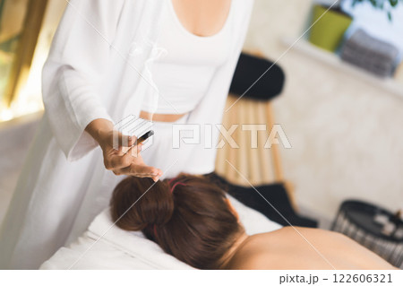 Female hand with smoking Palo Santo stick. Using fumigation during a massage session in salon, close-up, selective focus. 122606321