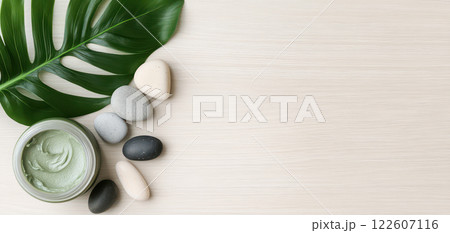 minimalistic spa scene featuring green clay mask, smooth stones, and tropical leaf creates serene atmosphere for relaxation and self care 122607116