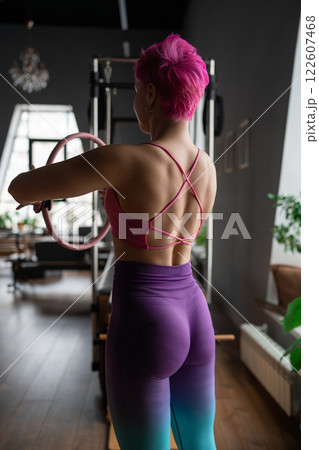 Young sporty attractive women doing pilates toning exercises for abs with flex ring toner, crunches to strengthen abdomen using pilates magic circle, and wearing sportswear in a yoga studio. Young sporty attractive women doing pilates toning exercises for abs with flex ring toner, crunches to strengthen abdomen using pilates magic circle, and wearing sportswear in a yoga studio. 122607468