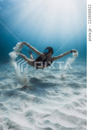 Freediver woman posing underwater with sand in hands. Freediving and beautiful sunlight with attractive woman. Freediver woman posing underwater with sand in hands. Freediving and beautiful sunlight with attractive woman. 122608922