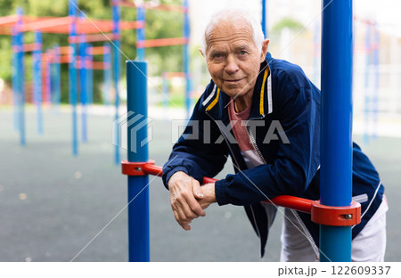 Old man in outdoor workout station Old man in outdoor workout station 122609337