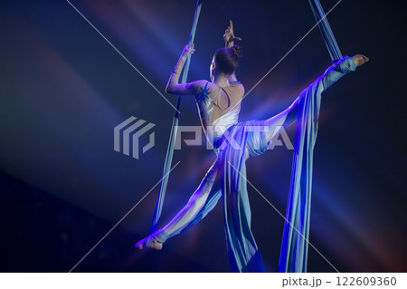 Performance by a circus acrobat artist. Girls perform aerial acrobatic elements on fabric. 122609360