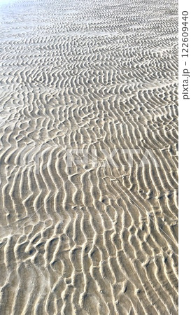 Ocean shapes sand patterns, beach texture forms wavy lines, wind sculpts sand ridges, shifting grains define ocean movement, smooth curves enhance beach texture. Ocean shapes sand patterns, beach texture forms wavy lines, wind sculpts sand ridges, shifting grains define ocean movement, smooth curves enhance beach texture. 122609440