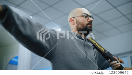 Airport Terminal: Security Officer Checks Passenger Body Using Metal Detector Airport Terminal: Security Officer Checks Passenger Body Using Metal Detector 122609642