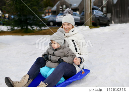 A mother with son sledding in the snow A mother with son sledding in the snow 122610258