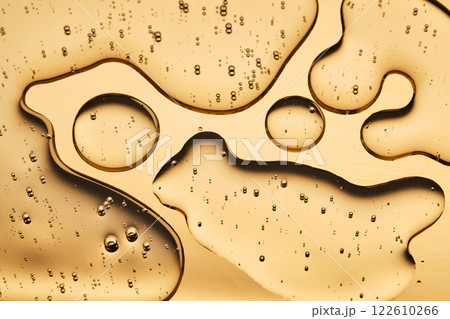 The beautiful texture of the cosmetic serum on a gold background that takes up most of the photo. The beautiful texture of the cosmetic serum on a gold background that takes up most of the photo. 122610266