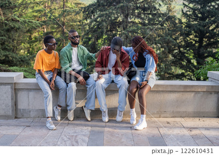 Stressed despaired African student almost cry due to failed exam or broke up, friends consoling peer 122610431