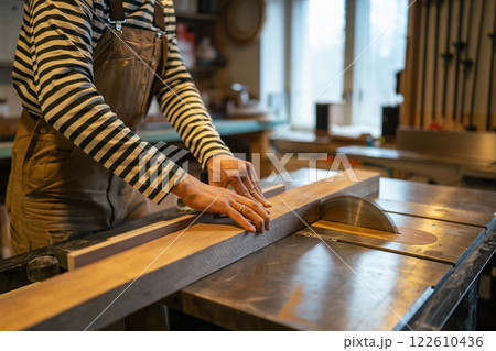 Carpenter hands with wood block on table saw, cut wood. Measuring and preparing beams for work 122610436