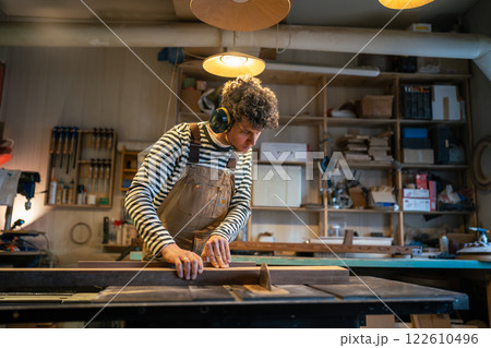 Dedicated male joiner works with circular saw, slicing wooden block with precision. Noise protection 122610496