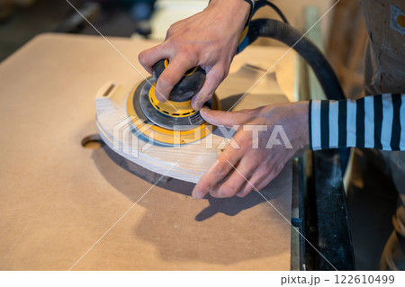 Closeup of sanding wood with orbital sander at workshop. Carpentry workshop. Furniture production Closeup of sanding wood with orbital sander at workshop. Carpentry workshop. Furniture production 122610499