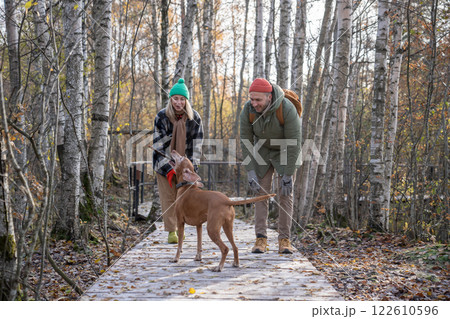 Happy family couple dog owners playing together with dog walking in autumn Scandinavian park. Happy family couple dog owners playing together with dog walking in autumn Scandinavian park. 122610596