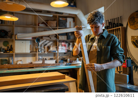 Craftsman inspects table legs and base, ensuring even surfaces and quality construction in workshop Craftsman inspects table legs and base, ensuring even surfaces and quality construction in workshop 122610611