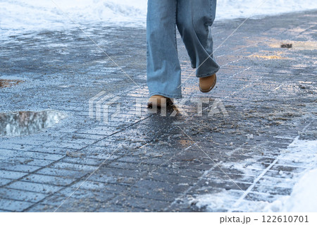 Anti-icing chemicals. Woman walking on the street treated with technical salt or de-icing chemicals 122610701