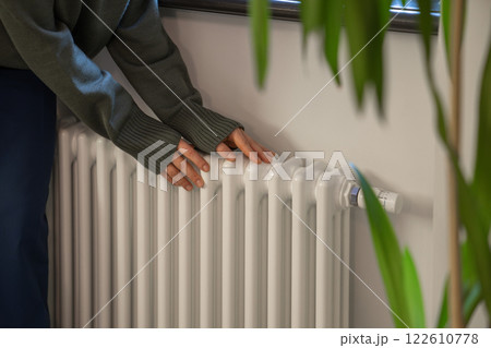 Woman heating hands on home radiator in cold winter season in well-maintained modern building. Woman heating hands on home radiator in cold winter season in well-maintained modern building. 122610778