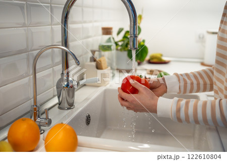 Fresh vegetable red paprika pepper washing with hand in home kitchen. Healthy vegetarian raw food. 122610804
