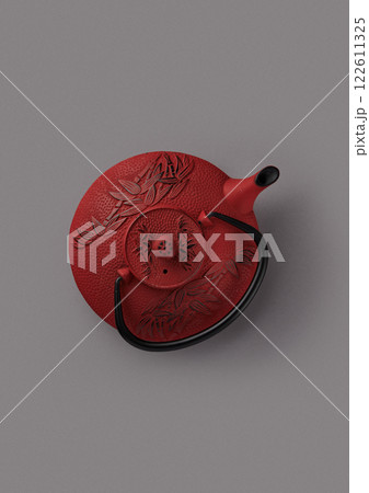 top shot on gray background beautiful red traditional Chinese teapot for tea ceremonies decorated with bamboo pattern black handle thin spout textured object 122611325