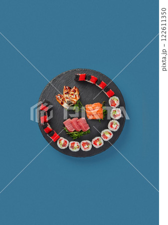 patterned sushi and sashimi on a blue background on a black plate professional cooking by Japanese chef traditional decor a lot of seafood 122611350