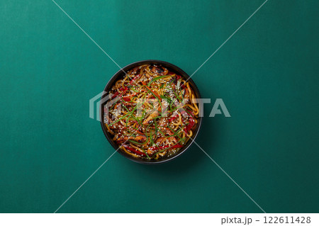 top shot on green background black salad plate with Chinese noodles noodles with veal slices Asian cuisine healthy eating sprinkled with sesame seeds 122611428