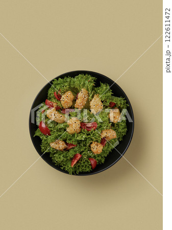 top shot on yellow background in a round black bowl lie lettuce leaves decorated with fried pieces of chicken and halves of cherry tomatoes healthy food top shot on yellow background in a round black bowl lie lettuce leaves decorated with fried pieces of chicken and halves of cherry tomatoes healthy food 122611472