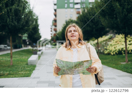 Portrait beautiful woman with paper map on urban street. Young worried female traveler using map lost in the city. Vacation concept by exploring interesting places to travel. Portrait beautiful woman with paper map on urban street. Young worried female traveler using map lost in the city. Vacation concept by exploring interesting places to travel. 122612796