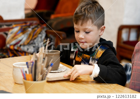 A boy creates a pot in a pottery workshop A boy creates a pot in a pottery workshop 122613182