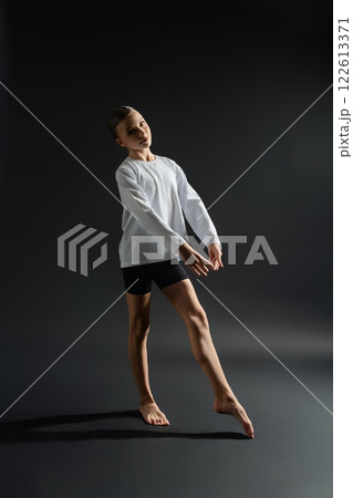 Young girl gracefully dancing in studio with dramatic lighting 122613371