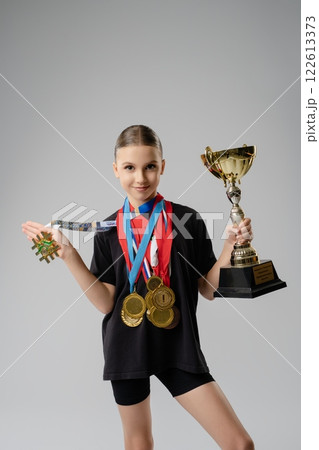 Young dancer shows off her trophies and medals from a great competition Young dancer shows off her trophies and medals from a great competition 122613373