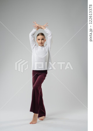 Girl showcases elegant dance pose in artistic setting during performances Girl showcases elegant dance pose in artistic setting during performances 122613378