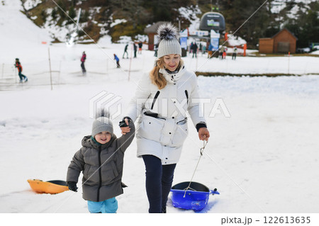 A mother with son sledding in the snow A mother with son sledding in the snow 122613635