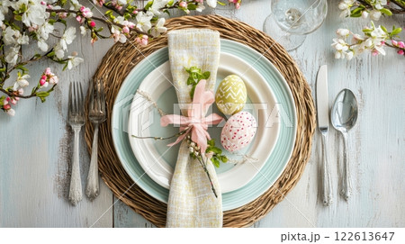 an elegant Easter table setting featuring a rustic woven charger plate, pastel ceramic dishes, decorative eggs 122613647