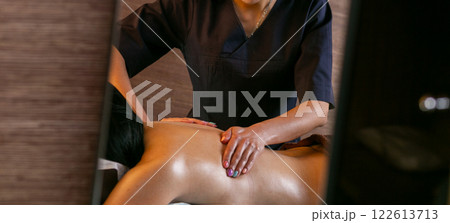 A female masseur massages a woman's back and neck. 122613713