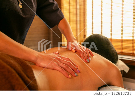 A female masseur massages a woman's back and neck. 122613723