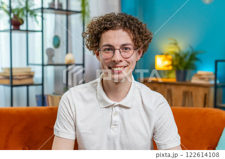 Portrait of happy young Caucasian man sitting on orange sofa looking at camera and smiling at home Portrait of happy young Caucasian man sitting on orange sofa looking at camera and smiling at home 122614108