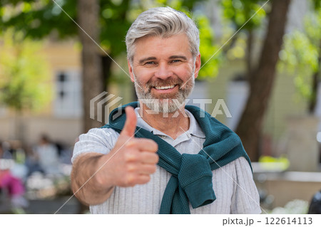 Happy mature man showing thumbs up like positive something good positive feedback on city street 122614113
