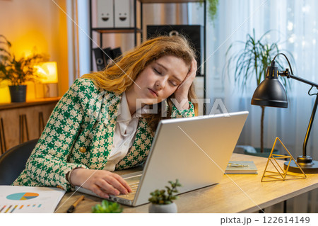 Bored sleepy businesswoman worker working on laptop computer leaning on hand at office desk 122614149