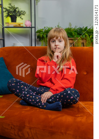 Preteen child girl presses finger to lips makes silence hush sign do not tell gossip secret, quiet 122614171