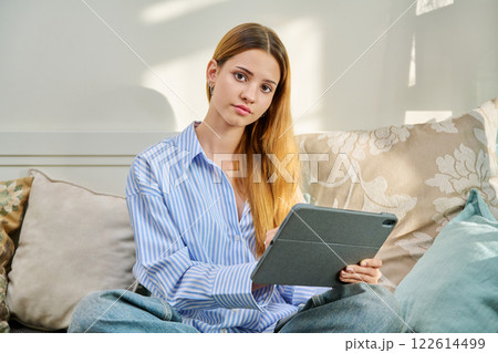 Portrait of female student on couch with digital tablet, studying at home 122614499