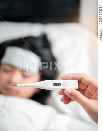 Caring Asian Parent Takes Temperature of Sick Asian Girl with Fever Using Digital Thermometer at Home. Caring Asian Parent Takes Temperature of Sick Asian Girl with Fever Using Digital Thermometer at Home. 122615054