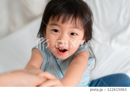 Joyful Child Reaching Out with a Bright Smile in a Cozy Indoor Setting Joyful Child Reaching Out with a Bright Smile in a Cozy Indoor Setting 122615063