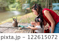 Asian Mother and Asian Daughter Painting Together in an Outdoor Art Workshop with Creative Atmosphere 122615072