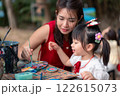 Asian Mother and Asian Daughter Painting Together in an Outdoor Art Workshop with Creative Atmosphere 122615073