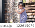 Young Asian Girl Playing on Rope Bridge in Natural Outdoor Setting with Greenery and Bright Sky 122615079